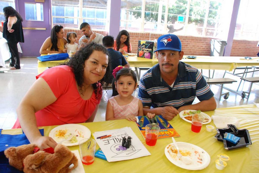 Parents and little daughter at canteen eating breakfast