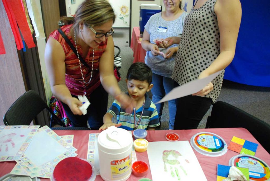 Women and little boy painting on table