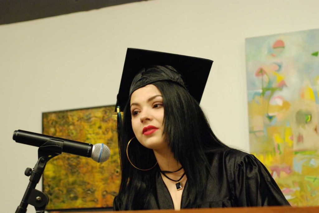 Women with graduation cap speaking on mic