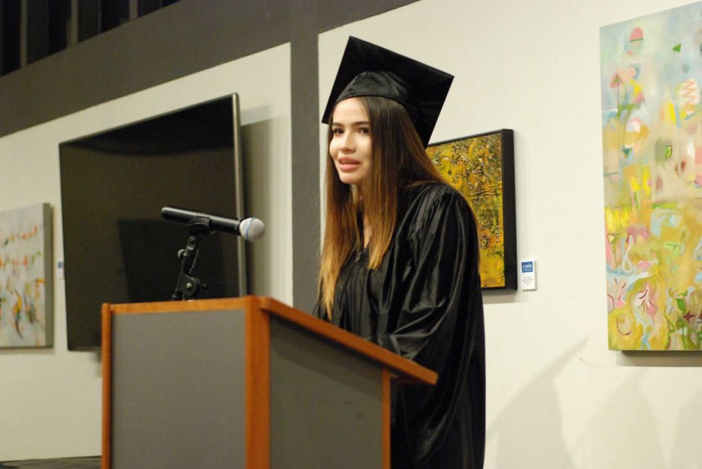 Women with graduation cap speaking on mic