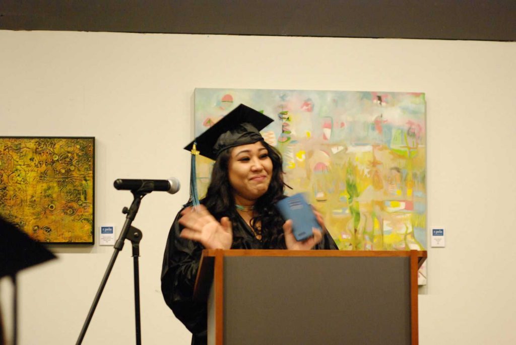 Women with graduation cap speaking on mic