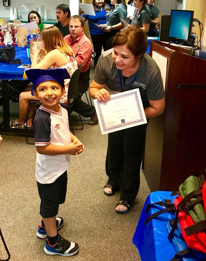 Team member giving certificate to little boy