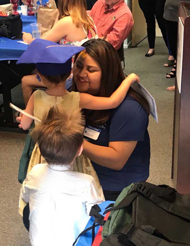 Team member giving hug to little girl