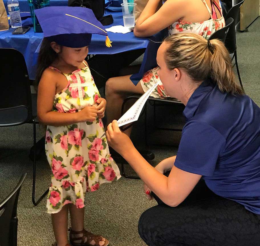 Team member giving certificate to little girl