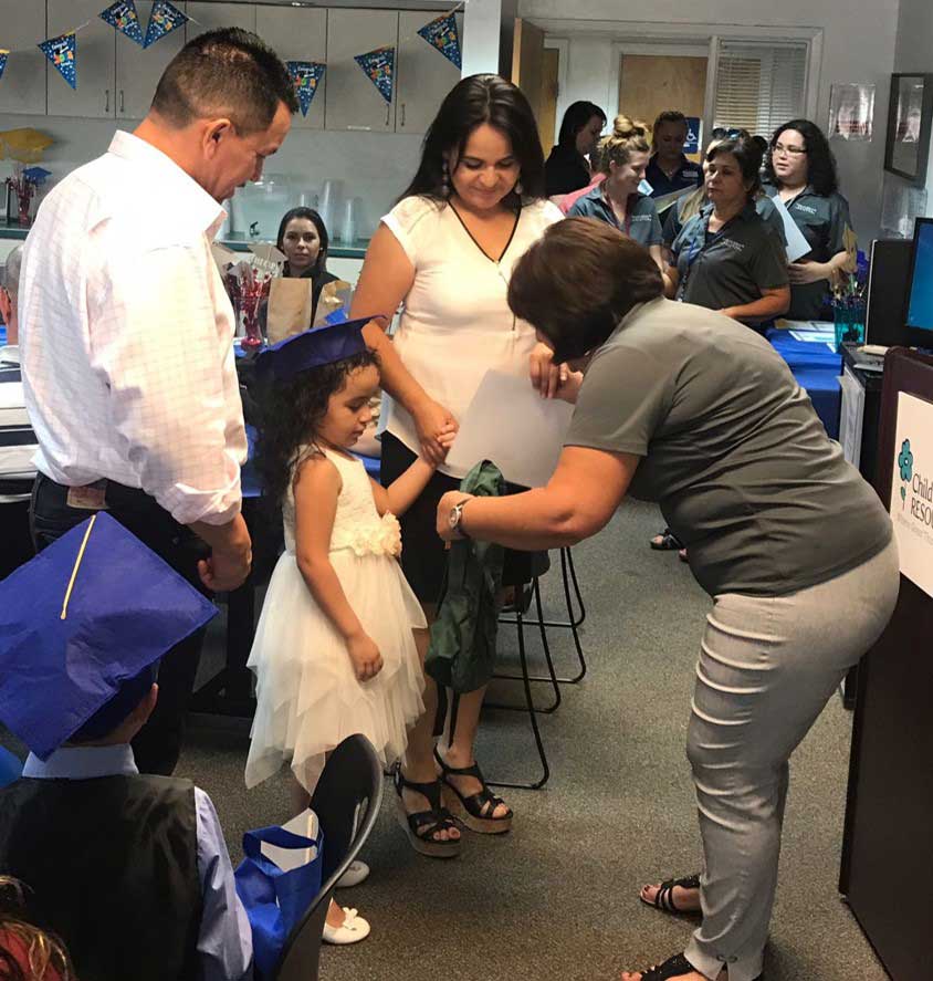 Team member giving certificate to little girl