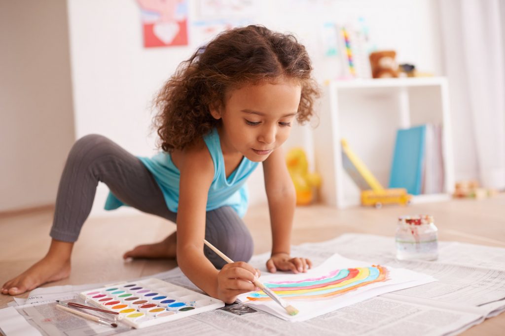 little girl painting a picture of a rainbow