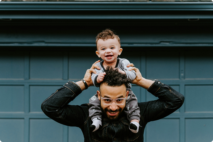 Smiling father with laughing baby on his shoulders