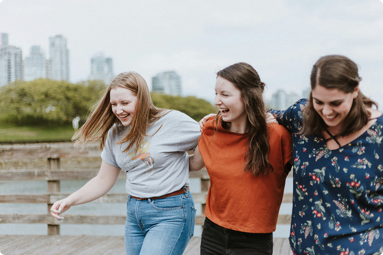 Three teenage girls laughing with and walking arm-in-arm