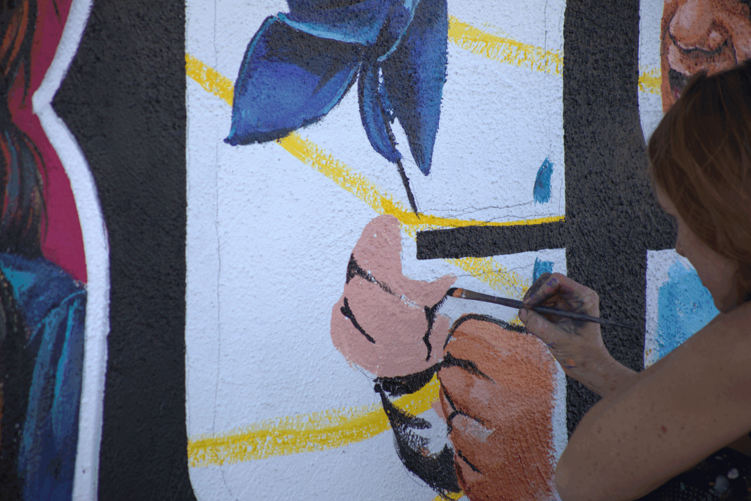 Artist painting a colorful mural on textured wall