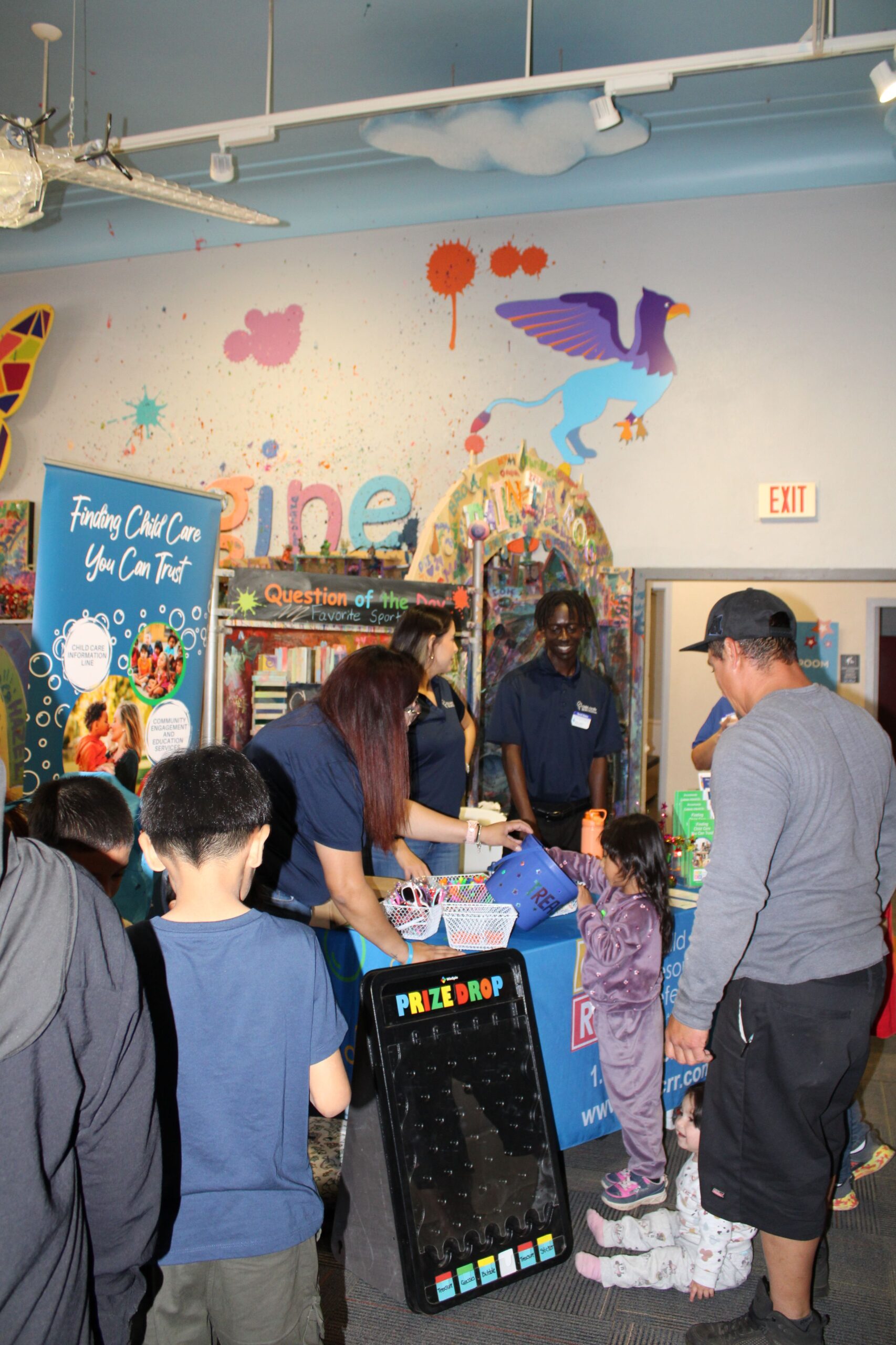 Children and staff at a colorful indoor outreach booth helping families