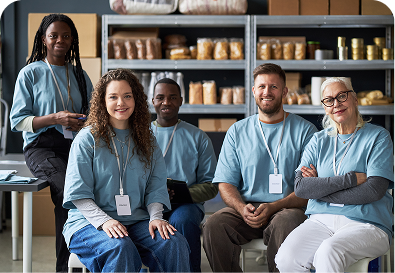 Five smiling volunteers in blue shirts working in a community center