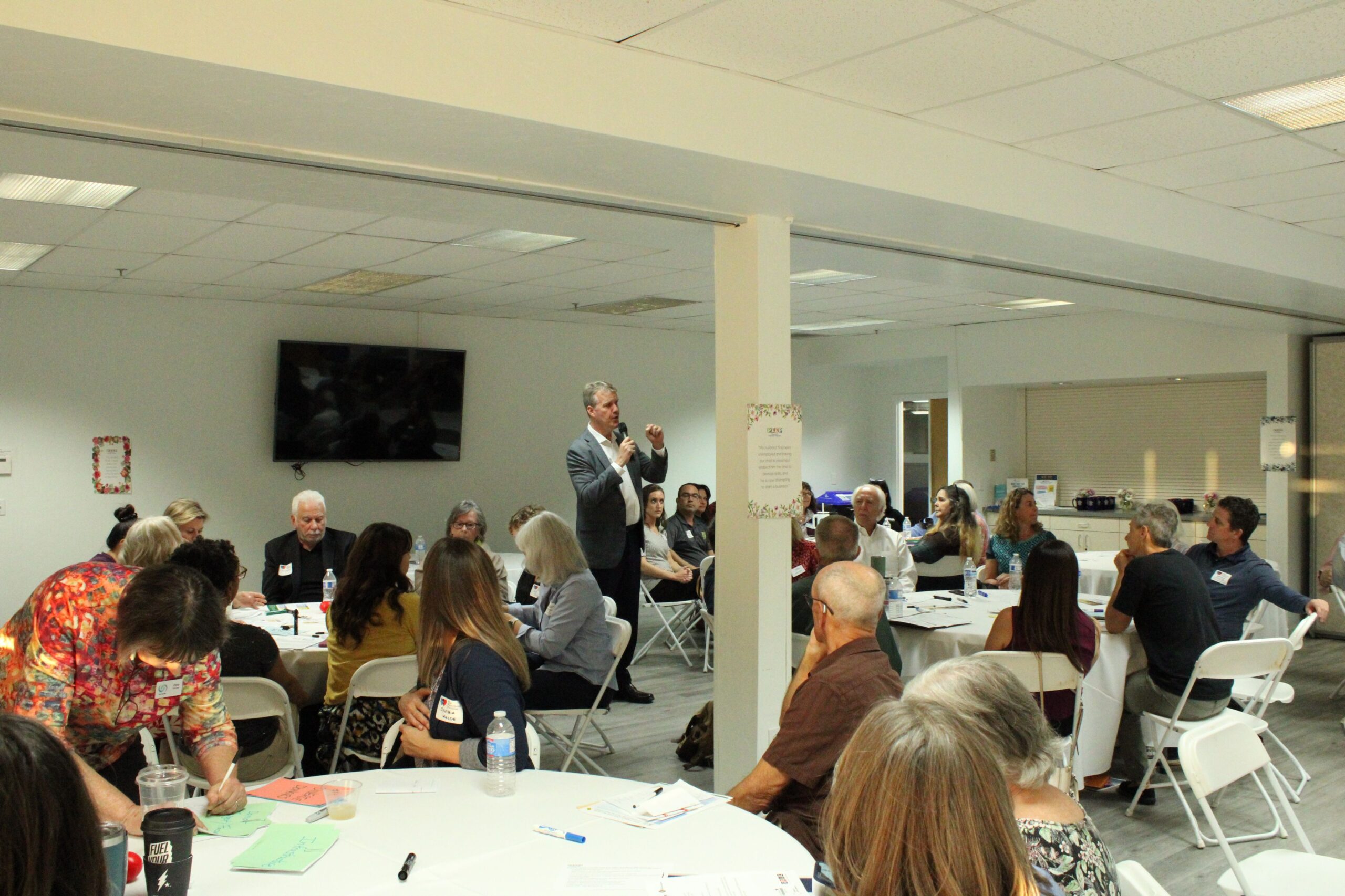 Child and Family Resources community meeting with man speaking with microphone to adults