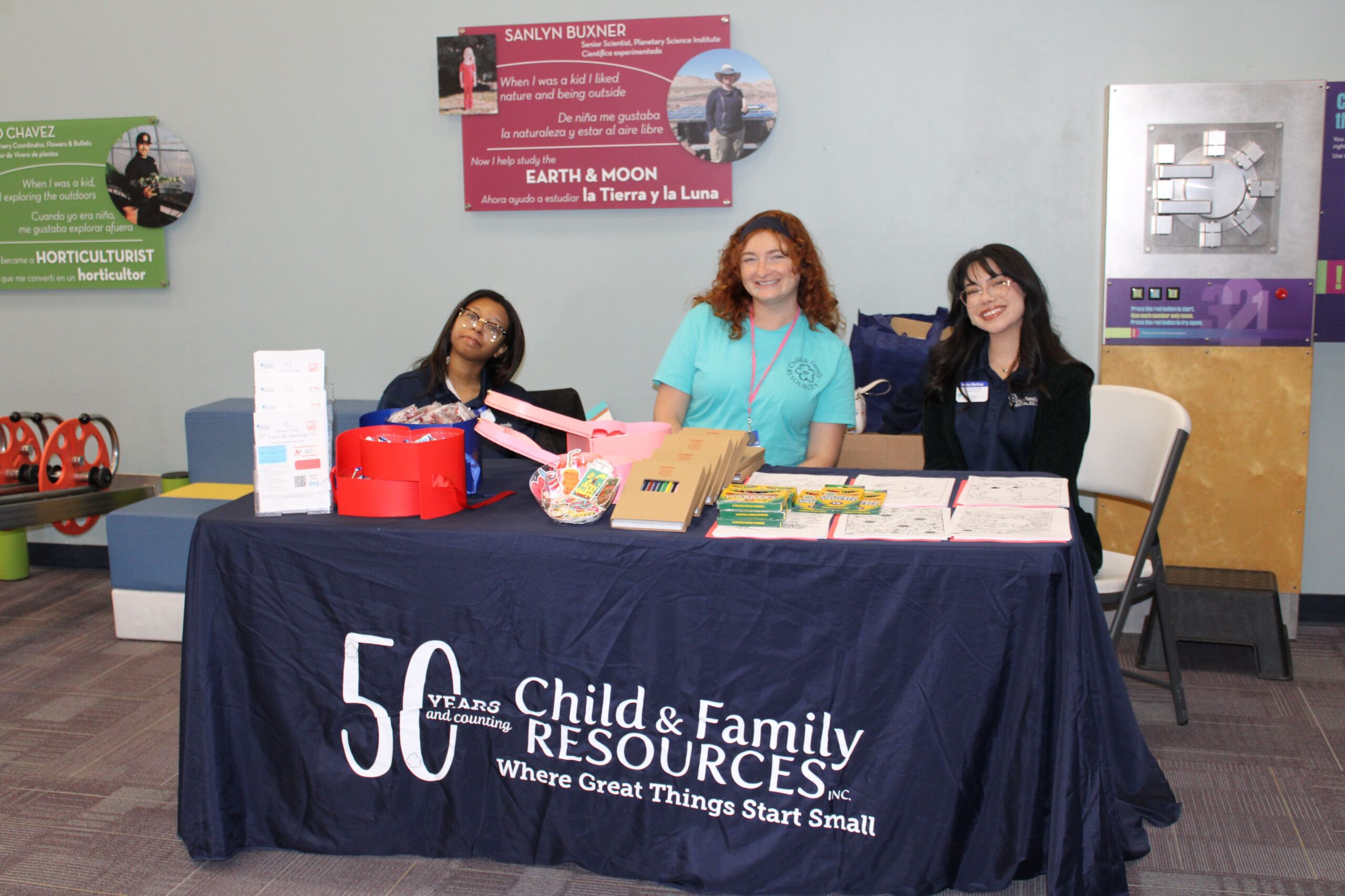 Three smiling staff at Child & Family Resources outreach table