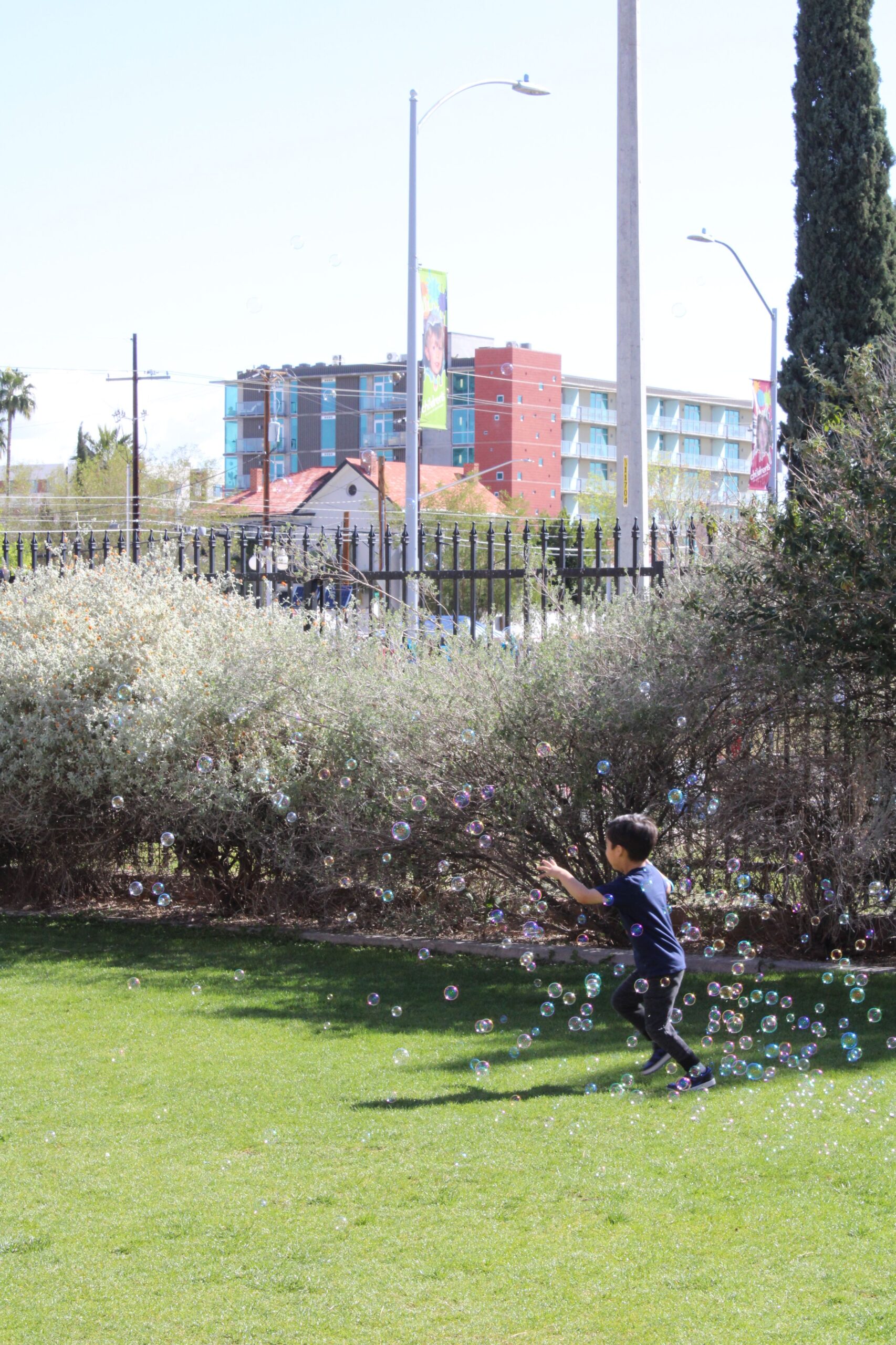 Young boy running through soap bubbles on green lawn