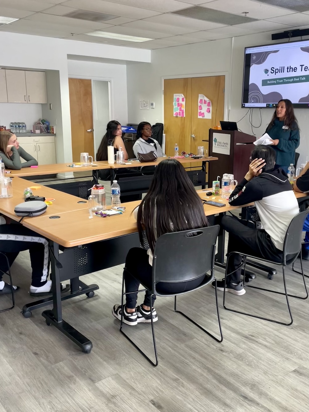 Youth leaders seated around a U-shaped conference table doing arts and crafts
