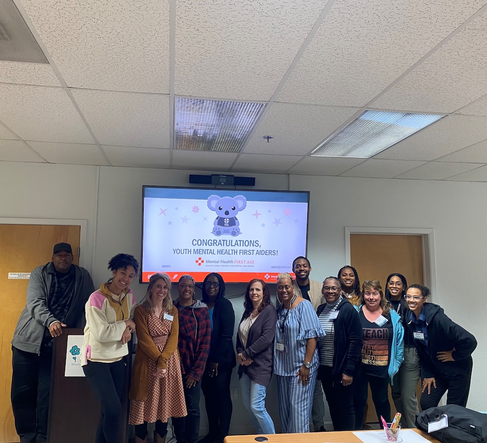 Smiling adults beneath screen reading CONGRATULATIONS, YOUTH MENTAL HEALTH FIRST AIDERS!