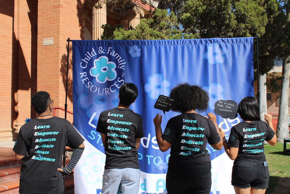 Youth leaders showing back of t-shirts that say: Learn, Empower, Advocate, Dedicate, Elevate, Resilience