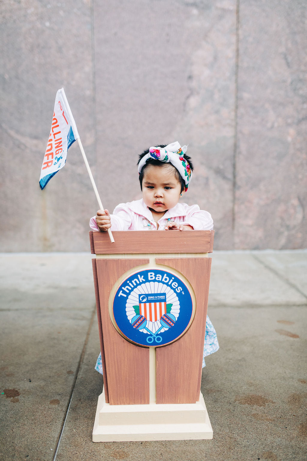 Toddler behind podium holding flag during Early Childhood Day at the Arizona capitol