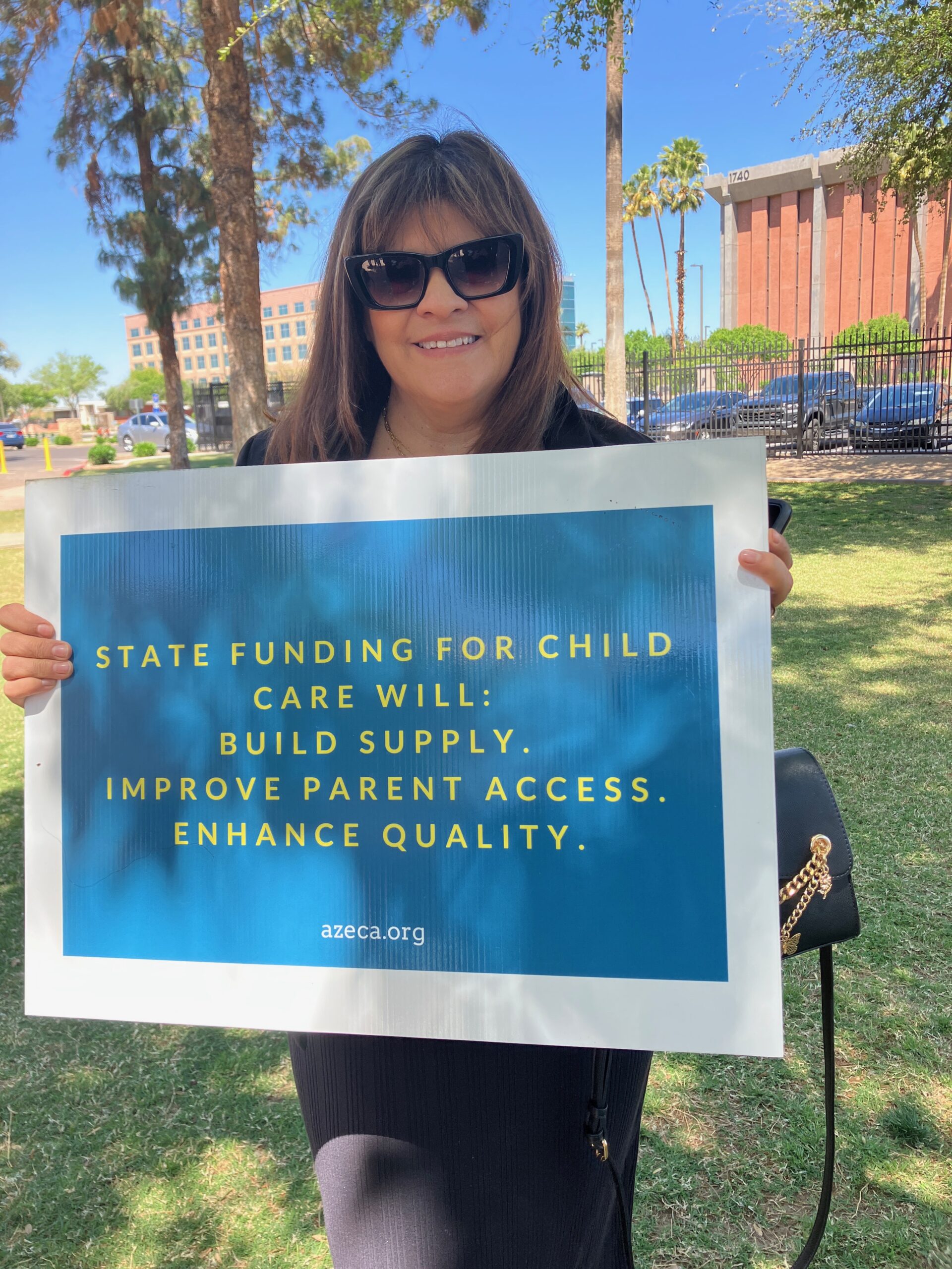 Woman holds sign that says: STATE FUNDING FOR CHILD CARE WILL: BUILD SUPPLY. IMPROVE PARENT ACCESS. ENHANCE QUALITY. azeca.org