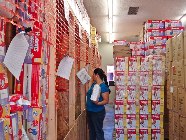 Woman in a supply warehouse beside stacks of diaper boxes