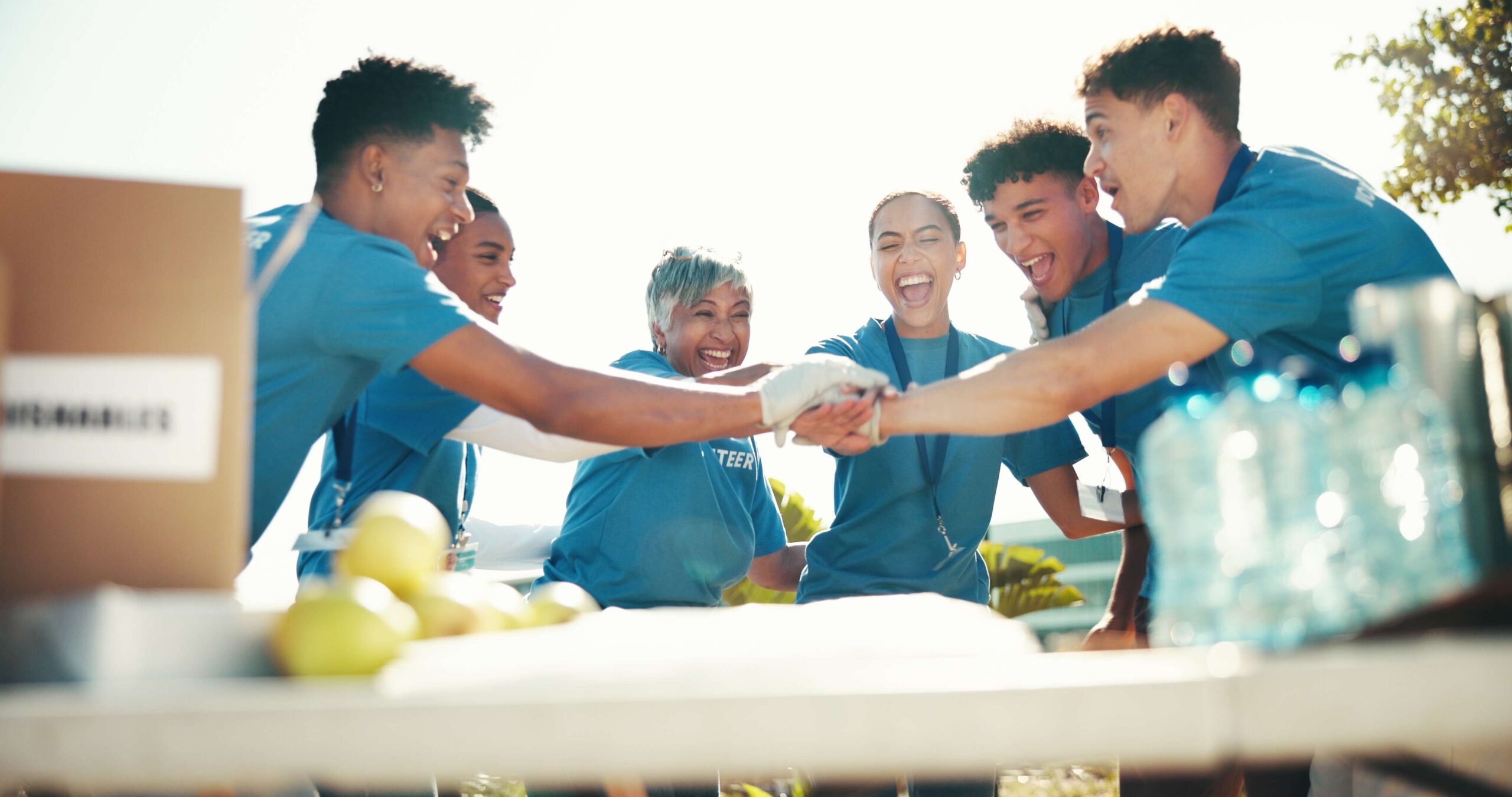 Smiling volunteers in blue shirts joining hands